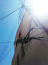 Low angle view of electricity pylon against blue sky