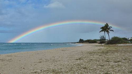 Scenic view of rainbow over sea against sky