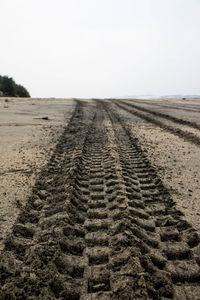 Dirt road amidst field against clear sky