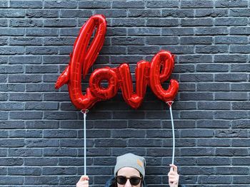 Low section of person holding red standing against wall