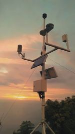 Low angle view of telephone pole against sky during sunset