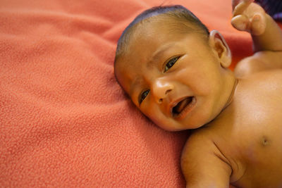 High angle portrait of shirtless baby boy crying while lying on bed