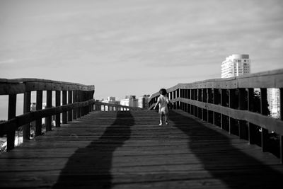 Rear view of child walking on footbridge