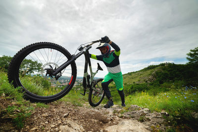 A man pushes a mountain bike up a hill. adventure travel by bike. guy athlete in defense lifts his