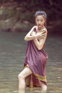 Portrait of young woman standing against lake