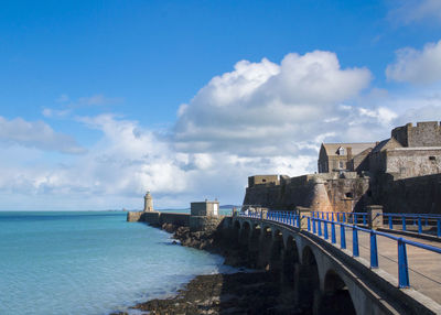 Bridge over sea against cloudy sky