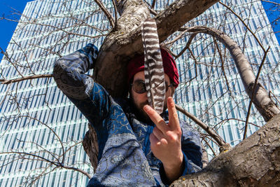 Low angle view of man holding rope against tree