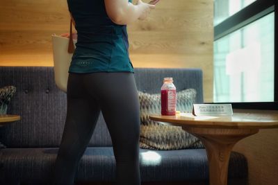 Low section of woman standing on table at home