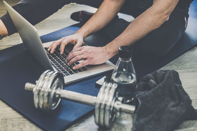 Sporty man resting after working out at home. fit boy looking gym exercise video on laptop computer.