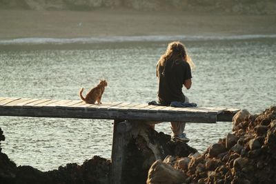 Woman sitting on beach by sea against sky