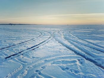 Snow covered field against sky during sunset