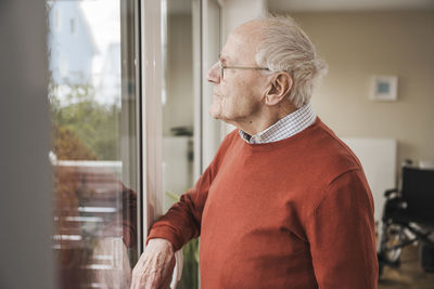 Thoughtful senior man looking through window