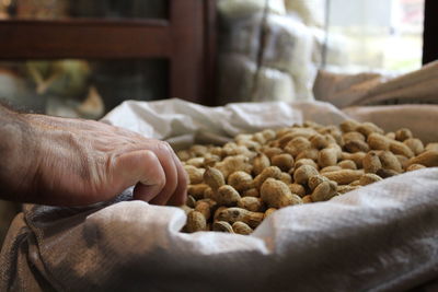 Cropped image of hand taking groundnuts in sack