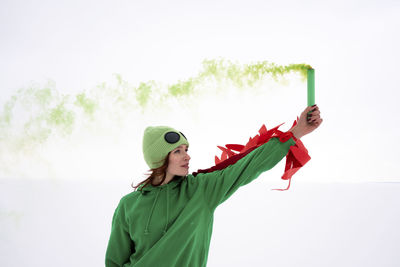 Woman holding distress flare in air against sky