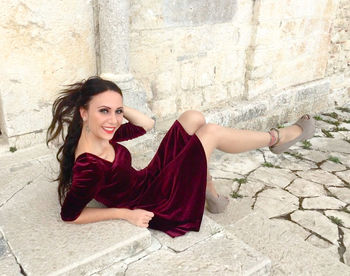 Portrait of smiling woman sitting against wall