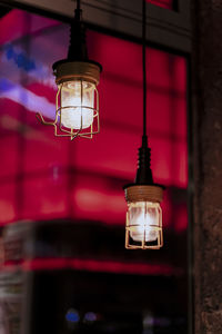 Low angle view of illuminated lamp hanging on wall in building