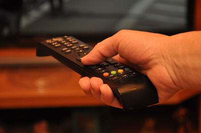 Close-up of cropped hand holding remote control