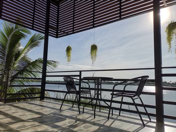 Table and chairs against sky seen through window