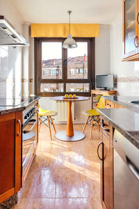 Interior of kitchen on two fronts with dining area next to the window