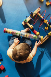 High angle view of baby boy playing with toys while sitting on floor at home