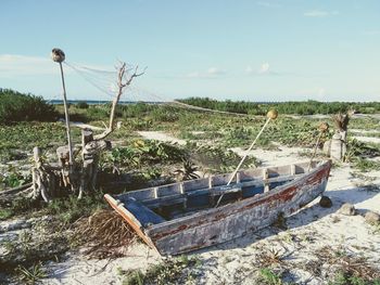 Abandoned boats moored on land against sky