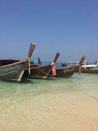 Boats in calm sea against clear sky