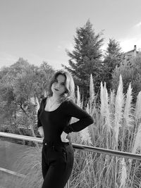 Portrait of woman standing by plants against sky