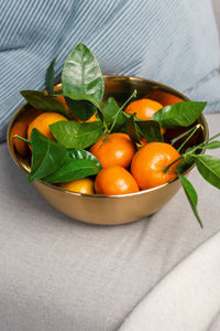 Copper bowl of tangerines on an armchair in a cozy warm room.