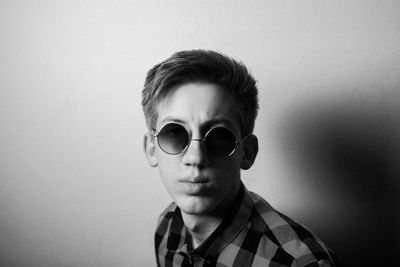 Portrait of young man wearing sunglasses against wall