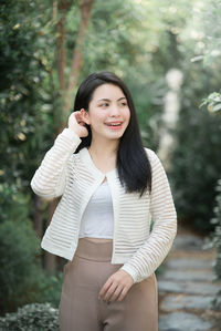 Portrait of young woman standing against tree