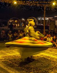 Blurred motion of people at illuminated carousel at night