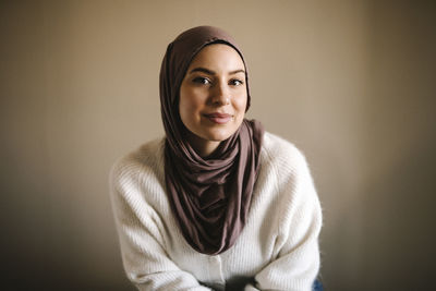 Smiling young woman in hijab against beige background