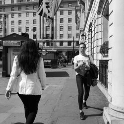 Full length of woman walking on street against buildings in city