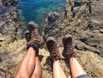 Low section of friends sitting on rock