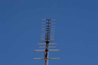 Low angle view of telephone pole against clear blue sky