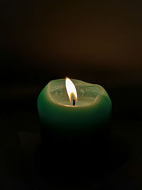 Close-up of lit tea light candle in darkroom