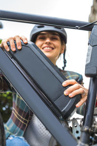 Young woman holding an electric bike battery mounted on frame