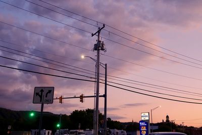Low angle view of road sign against sky at sunset
