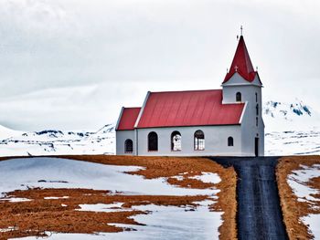 Building on snow covered field against sky