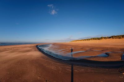 Scenic view of beach against blue sky