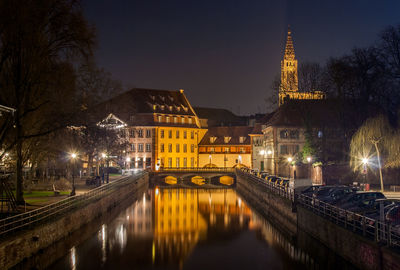 Illuminated bridge over river amidst buildings in city at night