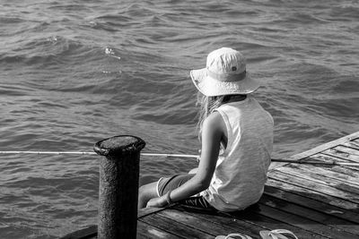 Girl fishing while sitting on a wooden jetty