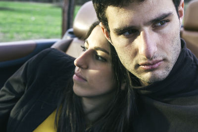 Portrait of young man sitting with his girlfriend in a convertible