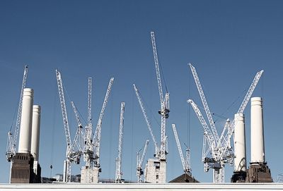 Low angle view of cranes against clear sky