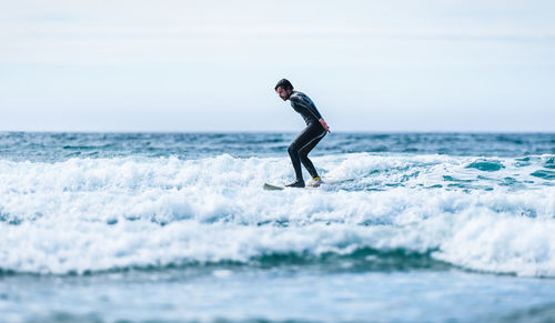 Man surfing in sea against sky