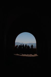 Silhouette people seen through arch window
