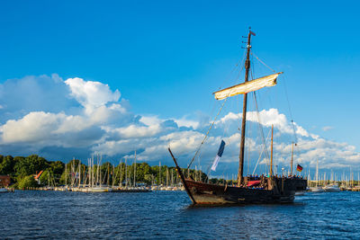 Fishing boat sailing in sea against blue sky