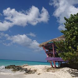 Lifeguard hut on beach against blue sky