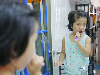 Girl looking at camera while standing in mirror