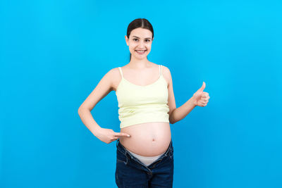 Portrait of smiling young woman against blue background